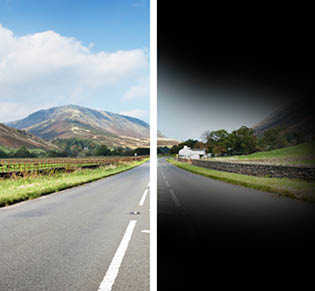 An image of a landscape with a road running through, split into two. One side shows a clear view	, and the other shows black shadows at the top and bottom of the image, obscuring the view.