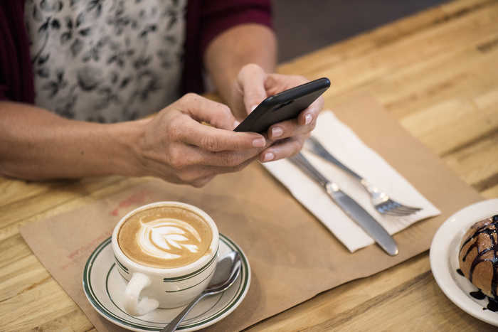 Person holding a phone on its hands in a coffee shop