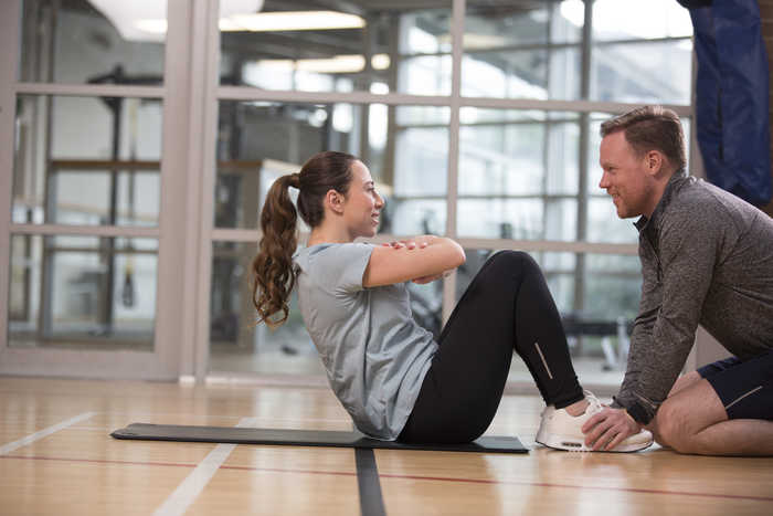 A woman doing push-up with a coach